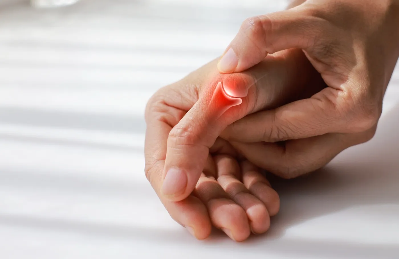 Hand gripping a painful thumb, with the arthritic joint at the base of the thumb highlighted